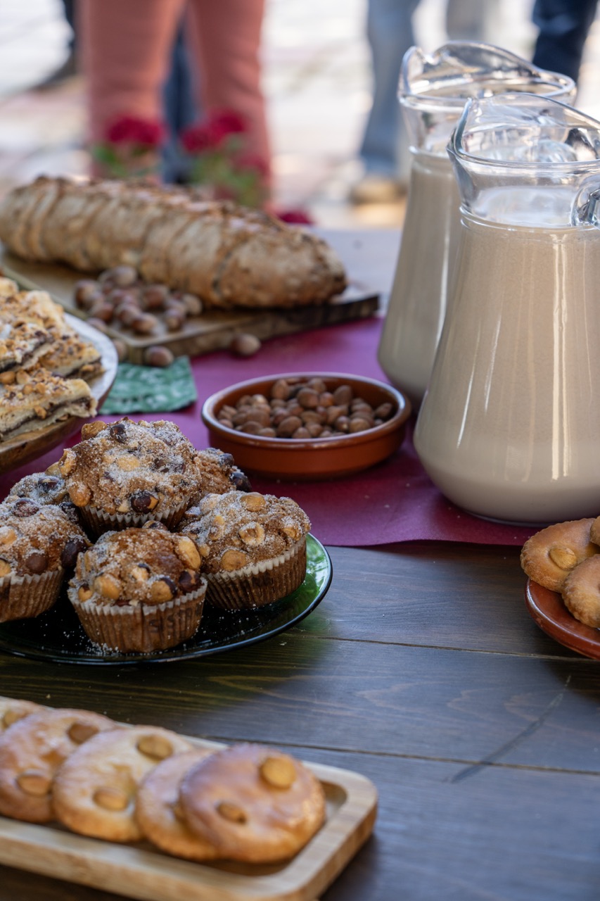 Taula amb avellanes, pastes i begudes en una activitat gastronòmica